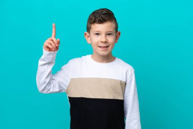Mavi arka planda izole edilmiş küçük çocuk harika bir fikre işaret ediyor.