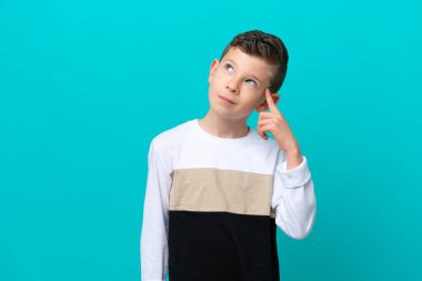 Küçük çocuk mavi arka planda izole edilmiş. Delilik jesti yapıyor. Parmağını kafaya koyuyor.