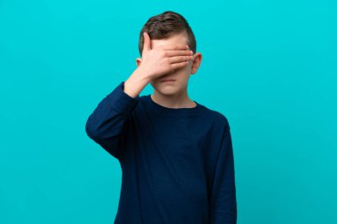 Küçük çocuk mavi arka planda tek başına, gözleri elleriyle kapatıyor. Bir şey görmek istemiyorum.