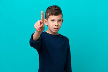Küçük çocuk mavi arka planda izole edilmiş ciddi bir ifadeye sahip birini sayıyor.