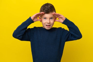 Sarı arka planda, sürpriz bir ifadeyle izole edilmiş küçük beyaz çocuk.