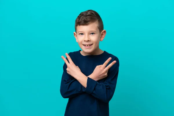 Malý Chlapec Izolovaný Modrém Pozadí Úsměvem Ukazující Znamení Vítězství — Stock fotografie
