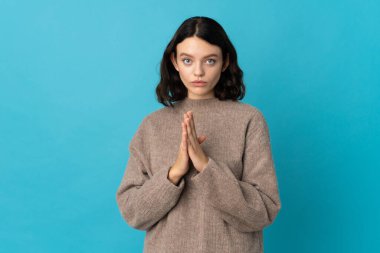 Mavi arka planda izole edilmiş genç Ukraynalı kız avuç içlerini bir arada tutuyor. İnsan bir şey ister.
