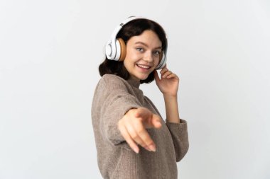 Genç Ukraynalı kız beyaz arka planda izole edilmiş müzik dinliyor ve ön tarafı işaret ediyor.