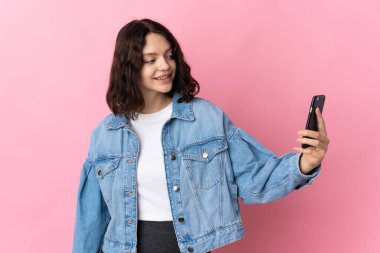 Pembe arka planda izole edilmiş genç Ukraynalı kız selfie çekiyor.