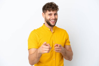 Beyaz arka planda izole edilmiş yakışıklı beyaz adam şaşırmış ve ön tarafı işaret ediyor.