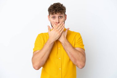 Beyaz arka planda izole edilmiş yakışıklı beyaz adam elleriyle ağzını kapatıyor.