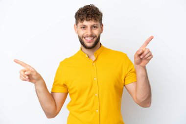 Beyaz arka planda izole edilmiş yakışıklı beyaz adam parmak uçlarını işaret ediyor ve mutlu.