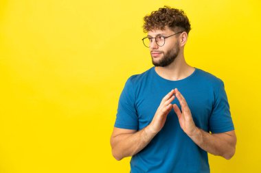 Sarı arka planda izole edilmiş yakışıklı beyaz adam bir şeyler planlıyor.