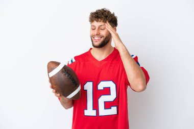 Beyaz arka planda ragbi oynayan beyaz bir adam çok fazla gülümsüyor.