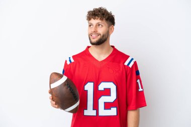 Beyaz arka planda ragbi oynayan beyaz tenli genç bir adam yukarı bakarken bir fikir düşünüyor.