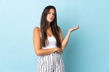 Mavi arka planda izole edilmiş genç Brezilyalı kadın kuşkuları var.