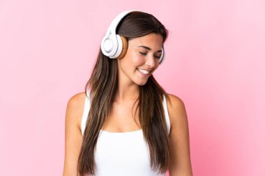 Pembe arka planda izole edilmiş genç Brezilyalı kız müzik dinliyor.