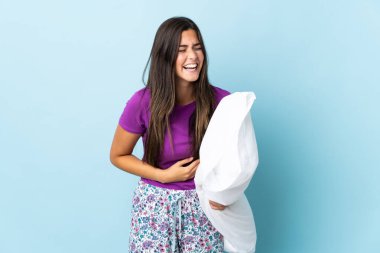 Mavi arka planda izole edilmiş pijamalı genç Brezilyalı kız, çok gülümsüyor.