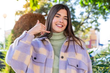 Parktaki genç Brezilyalı kadın telefon jesti yapıyor. Bana geri dönüş işareti ver.