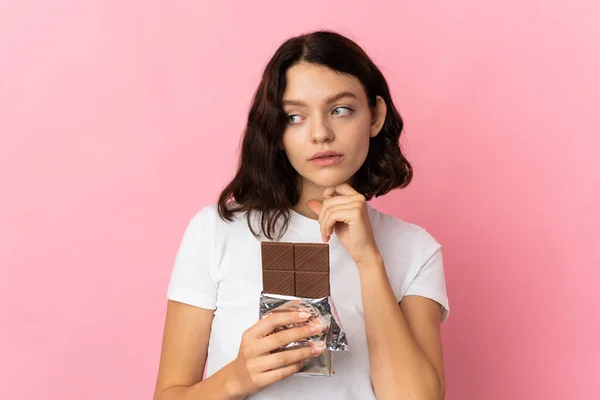 Teenager Ukrajinská Dívka Izolované Růžovém Pozadí Čokoládovou Tabletu Mají Pochybnosti — Stock fotografie