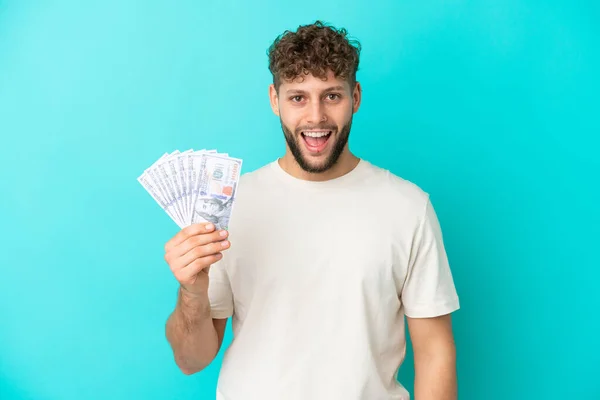 Νεαρός Καυκάσιος Παίρνει Πολλά Χρήματα Απομονωμένος Μπλε Φόντο Έκφραση Έκπληξη — Φωτογραφία Αρχείου