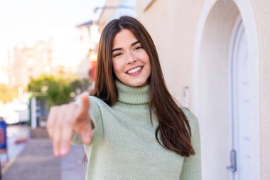Dışardaki genç Brezilyalı kadın kendine güvenen bir ifadeyle seni işaret ediyor.