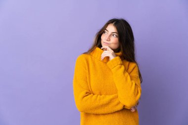 Genç beyaz kadın mor arka planda izole edilmiş ve yukarı bakıyor.