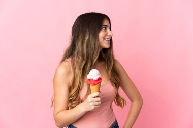 Pembe arka planda izole edilmiş kornet dondurmalı beyaz bir kadın.