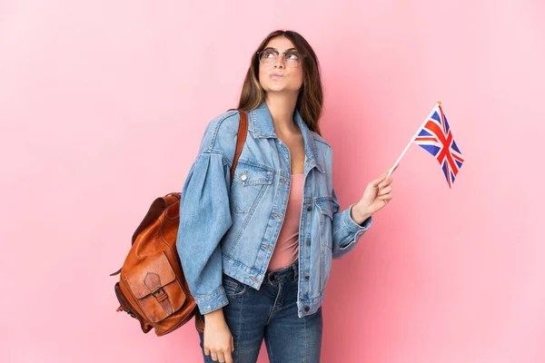 拿着英国国旗的年轻女子 背景为粉色 举着英国国旗向上张望 — 图库照片