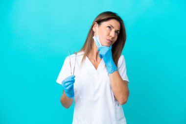 Mavi arka planda izole edilmiş orta yaşlı doktor kadının şüpheleri var.