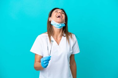 Orta yaşlı doktor kadın mavi arka planda yalnız gülüyor.