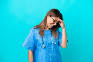 Orta yaşlı cerrah kadın mavi arka planda yalnız gülüyor.