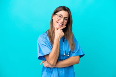 Mavi arka planda sırıtan orta yaşlı cerrah kadın.