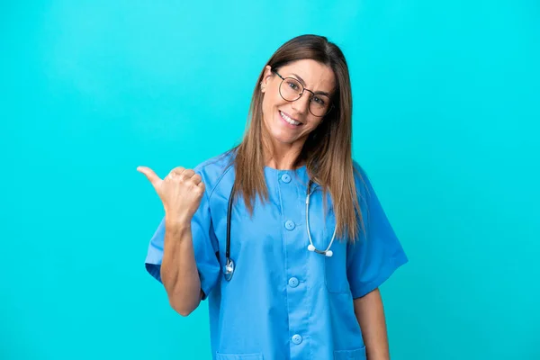 Chirurg Średnim Wieku Kobieta Izolowana Niebieskim Tle Wskazując Stronie Przedstawić — Zdjęcie stockowe
