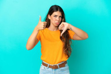 Mavi arka planda izole edilmiş beyaz bir kadın iyiye-kötüye işaret veriyor. Evet ya da hayır arasında kararsız