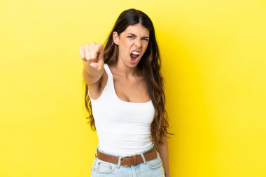 Sarı arka planda izole edilmiş genç beyaz kadın hayal kırıklığına uğramış ve ön tarafı işaret ediyor.