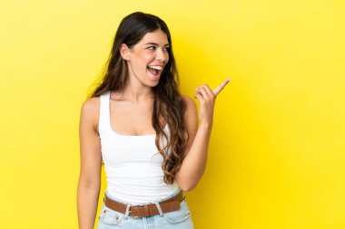 Sarı arka planda izole edilmiş genç beyaz kadın parmağını kaldırarak çözümü bulmaya çalışıyor.