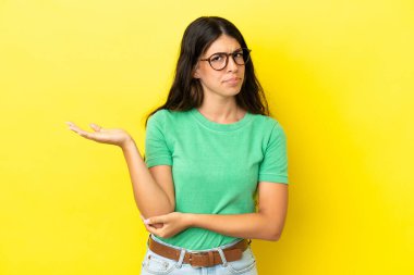 Sarı arka planda izole edilmiş genç beyaz kadın kuşkuları var.