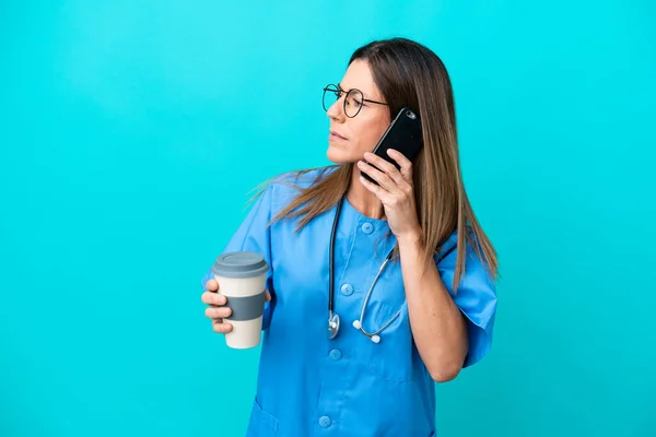 Medioevo Chirurgo Donna Isolato Sfondo Blu Con Caffè Portare Cellulare — Foto Stock