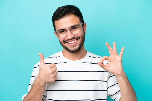 Młody Brazylijczyk Odizolowany Niebieskim Tle Okularach Robiący Znak — Zdjęcie stockowe