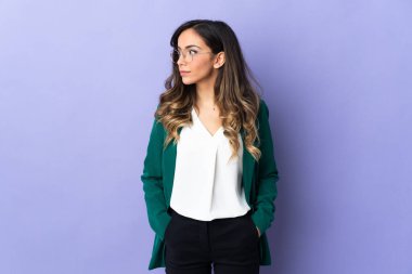 Mor arka planda izole edilmiş genç beyaz kadın yan tarafa bakıyor.