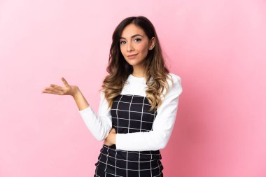 Pembe arka planda izole edilmiş genç beyaz kadın şüpheli hareketler yapıyor.