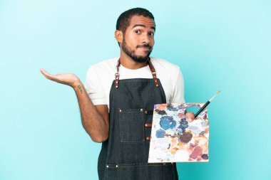 Mavi arka planda izole edilmiş bir palet tutan genç sanatçı ellerini kaldırırken şüpheleri var.