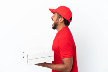 Pizza teslimatçısı beyaz arka planda izole edilmiş pizza kutularını alıyor ve yan pozisyonda gülüyor.