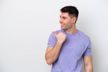 Beyaz arka planda izole edilmiş genç beyaz bir adam bir ürün sunmak için kenarı işaret ediyor.