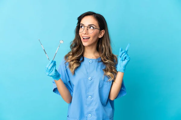 女牙医把工具放在蓝色背景的孤立的地方 认为这是一个指指点点的想法 — 图库照片