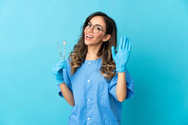Dentystka Trzyma Narzędzia Odizolowanym Niebieskim Tle Salutując Ręką Szczęśliwym Wyrazem — Zdjęcie stockowe