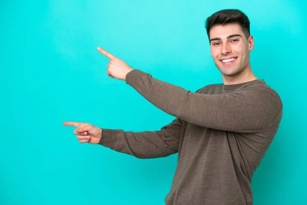 青い背景の指を横に向けて製品を提示する若い白人男性 — ストック写真