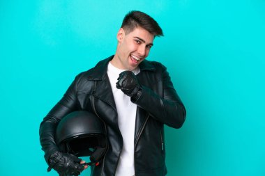 Mavi arka planda izole edilmiş motosiklet kasklı beyaz bir adam zaferi kutluyor.