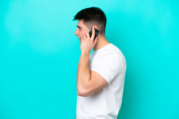 Ung Kaukasisk Mand Isoleret Blå Baggrund Holder Samtale Med Mobiltelefonen - Stock-foto