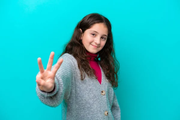 被蓝色背景隔离的小女孩快乐地数着三根手指 — 图库照片