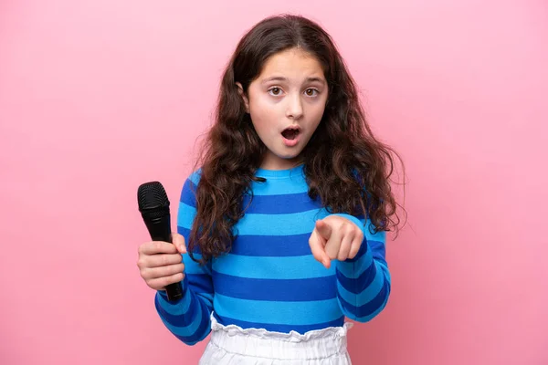 Malá Zpěvačka Dívka Vyzvednout Mikrofon Izolované Růžovém Pozadí Překvapen Ukazuje — Stock fotografie