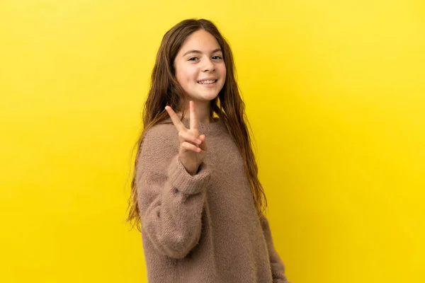 stock image Little caucasian girl isolated on yellow background smiling and showing victory sign