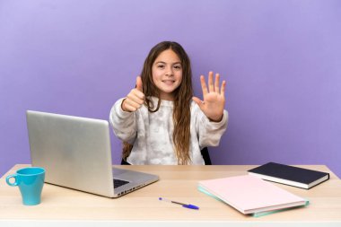 Mor arka planda dizüstü bilgisayarı olan küçük bir kız öğrenci. Parmaklarıyla altı kişi sayıyor.